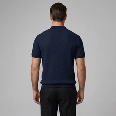 Man wearing a navy ribbed knit polo shirt on a gray background