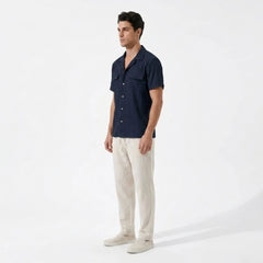 Man wearing a navy striped shirt and beige pants on a white background