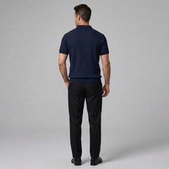Man wearing a navy sweater and black pants on a gray background