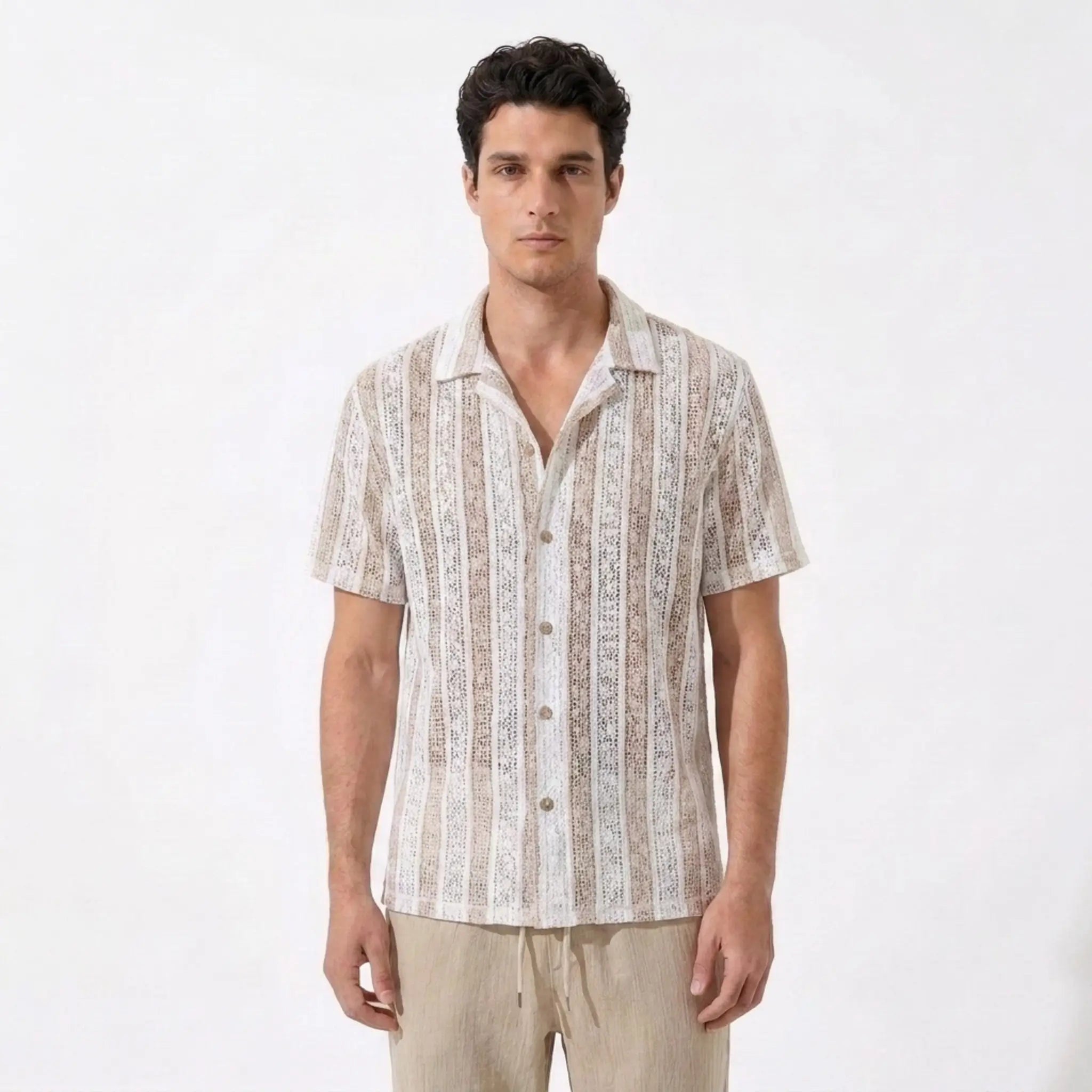 Man wearing a patterned shirt and beige pants on a white background