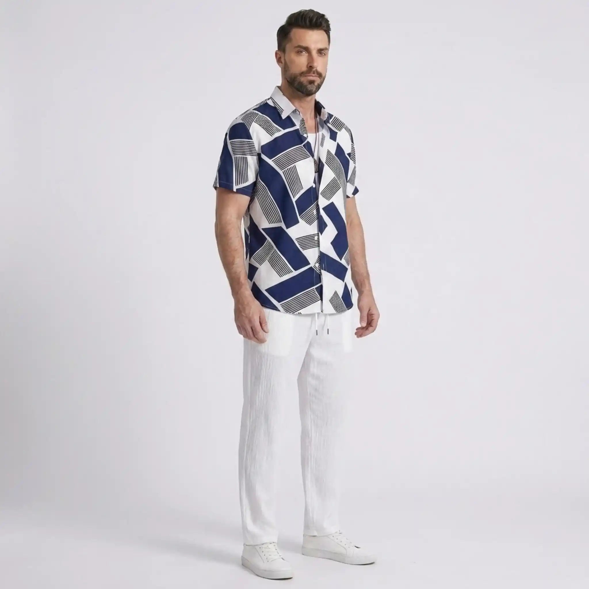 Man wearing a patterned shirt and white pants on a light gray background