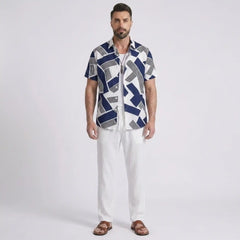 Man wearing a patterned shirt and white pants on a light gray background