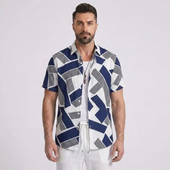 Man wearing a patterned shirt and white pants on a white background