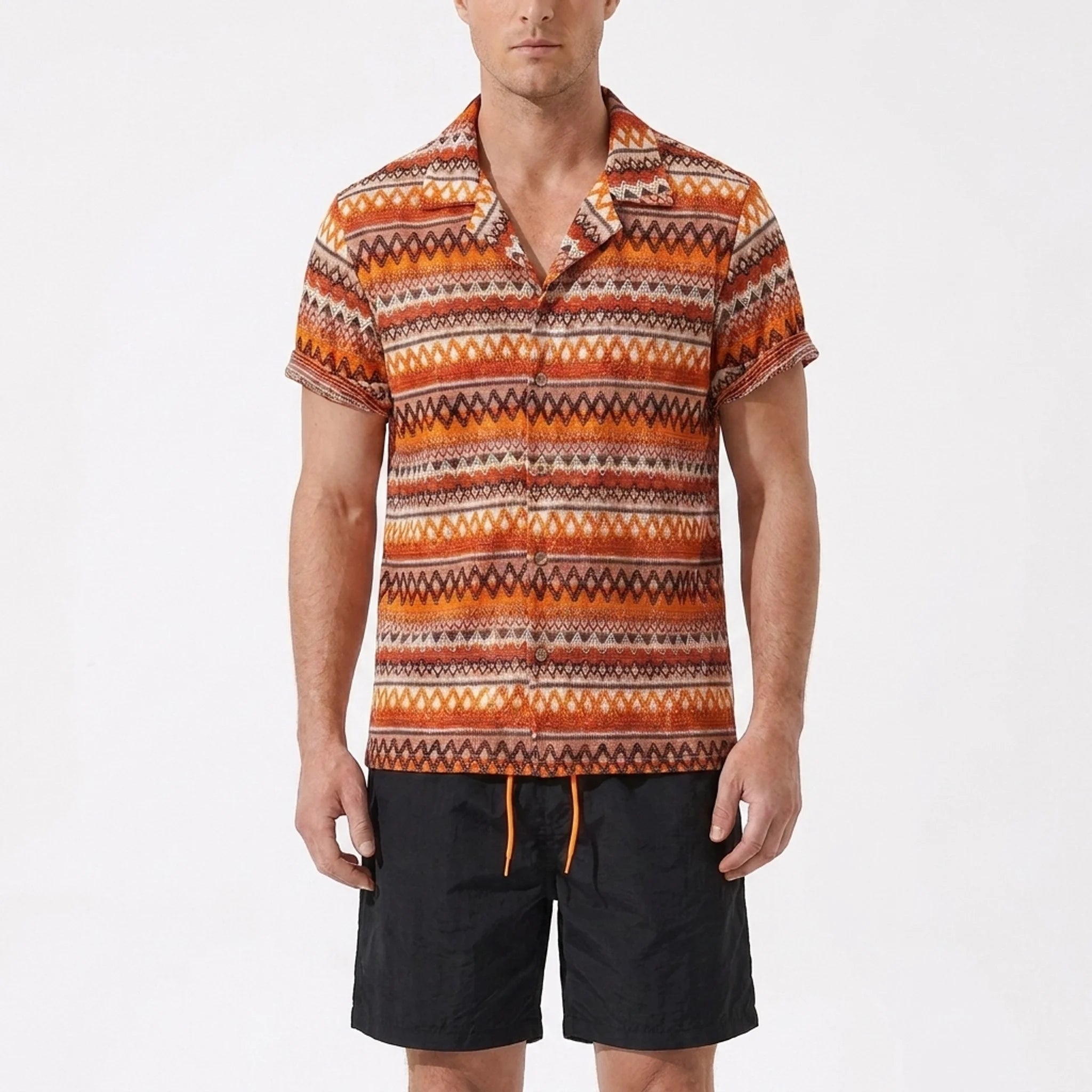 Man wearing a patterned shirt and black shorts on a white background