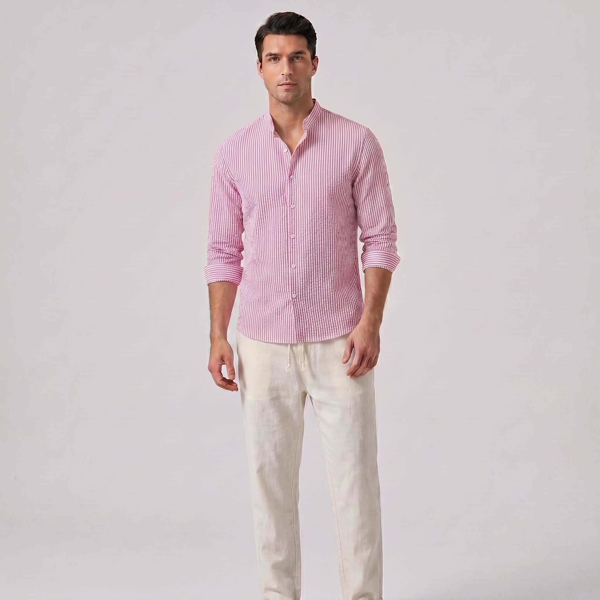 Man wearing a pink checkered shirt and white pants on a light gray background