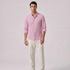 Man wearing a pink checkered shirt and white pants on a light gray background