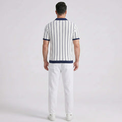 Man wearing a striped polo shirt and white pants on a light gray background
