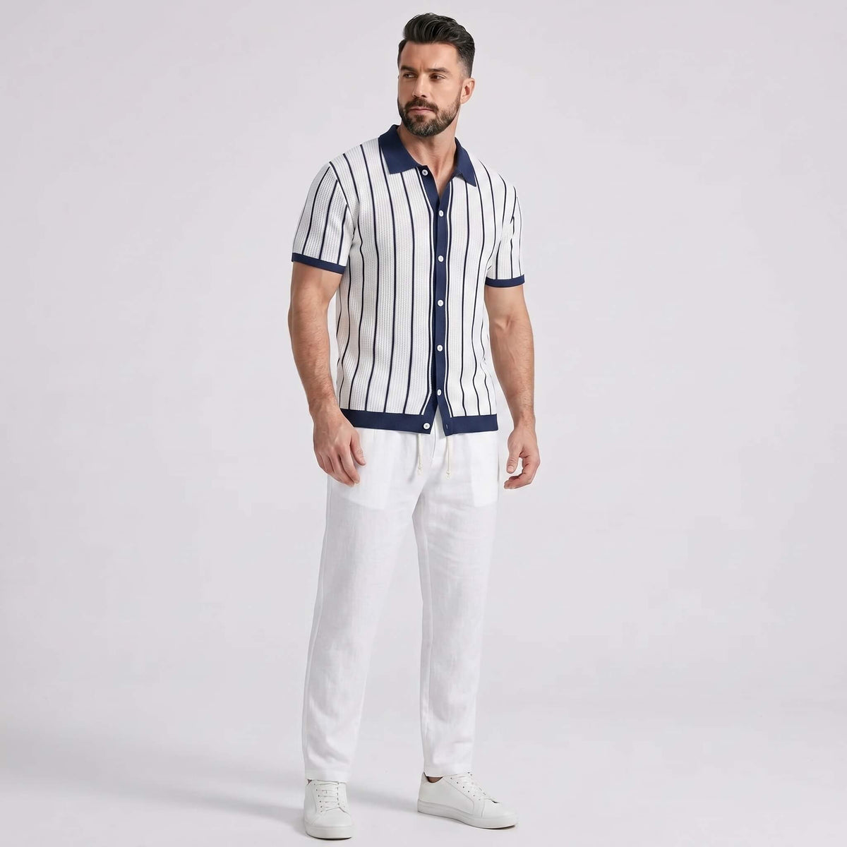 Man wearing a striped shirt and white pants on a light gray background