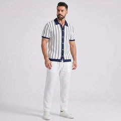Man wearing a striped shirt and white pants on a light gray background