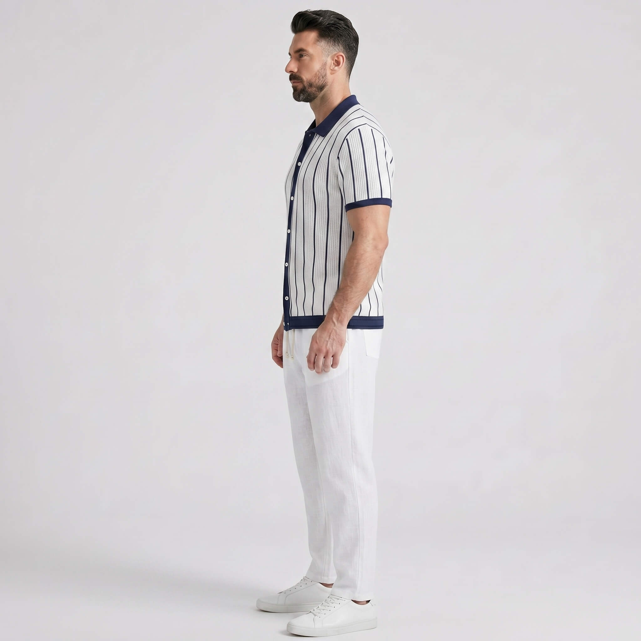 Man wearing a striped shirt and white pants on a plain background