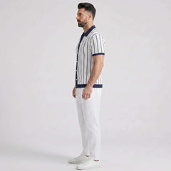 Man wearing a striped shirt and white pants on a plain background