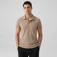 Man wearing a tan knitted polo shirt against a plain background
