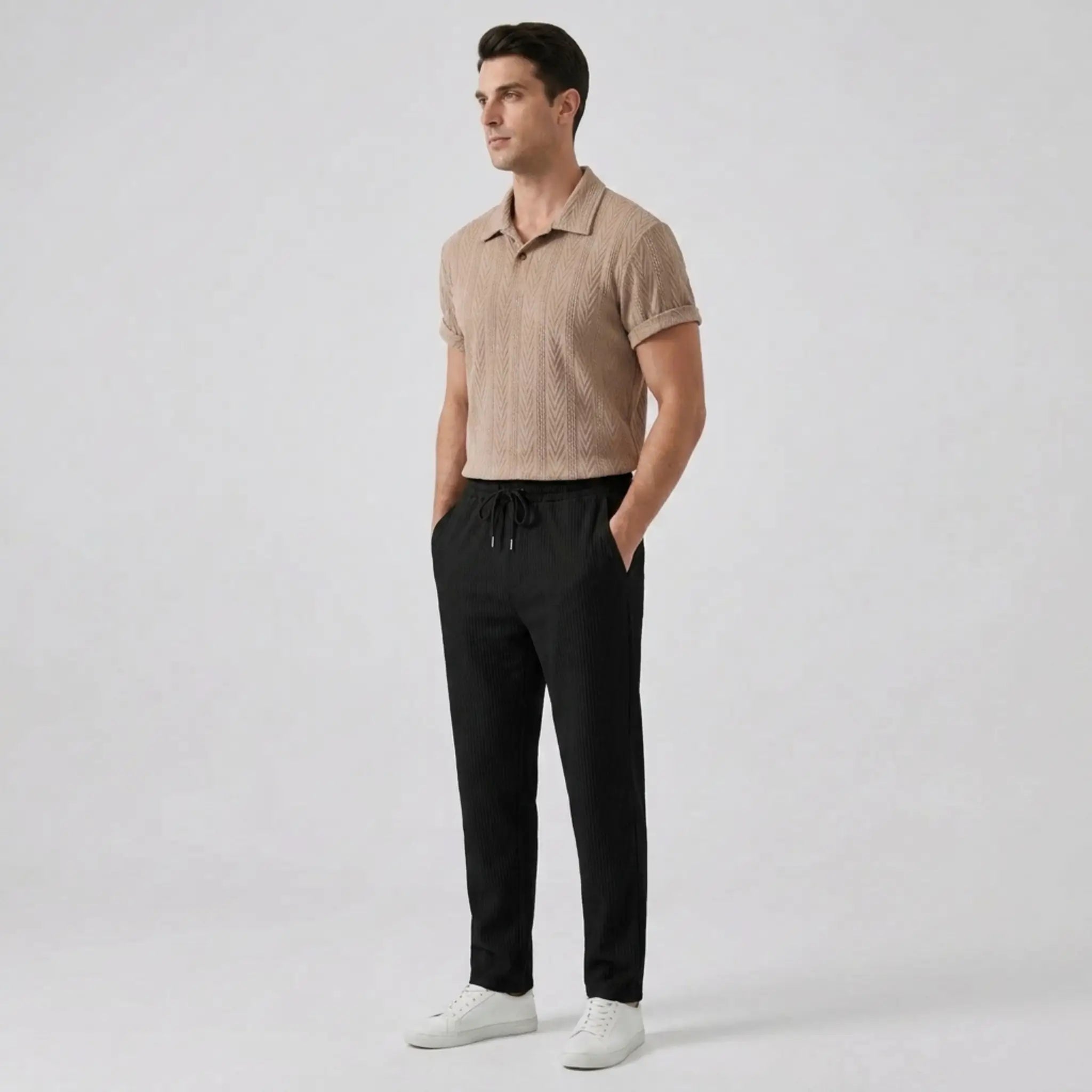 Man wearing a tan polo shirt and black pants side view on a light gray background