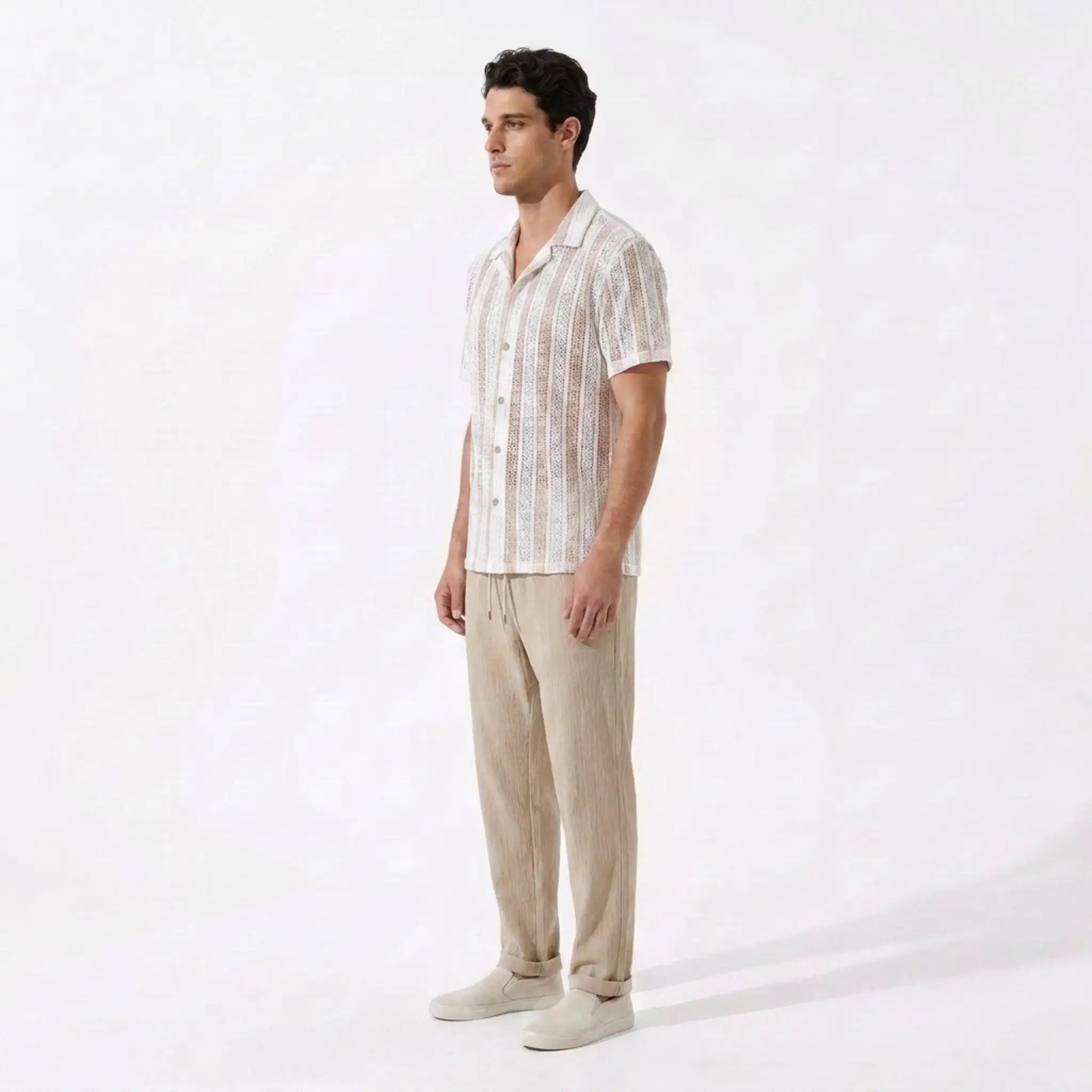 Man wearing a white patterned shirt and beige pants on a white background
