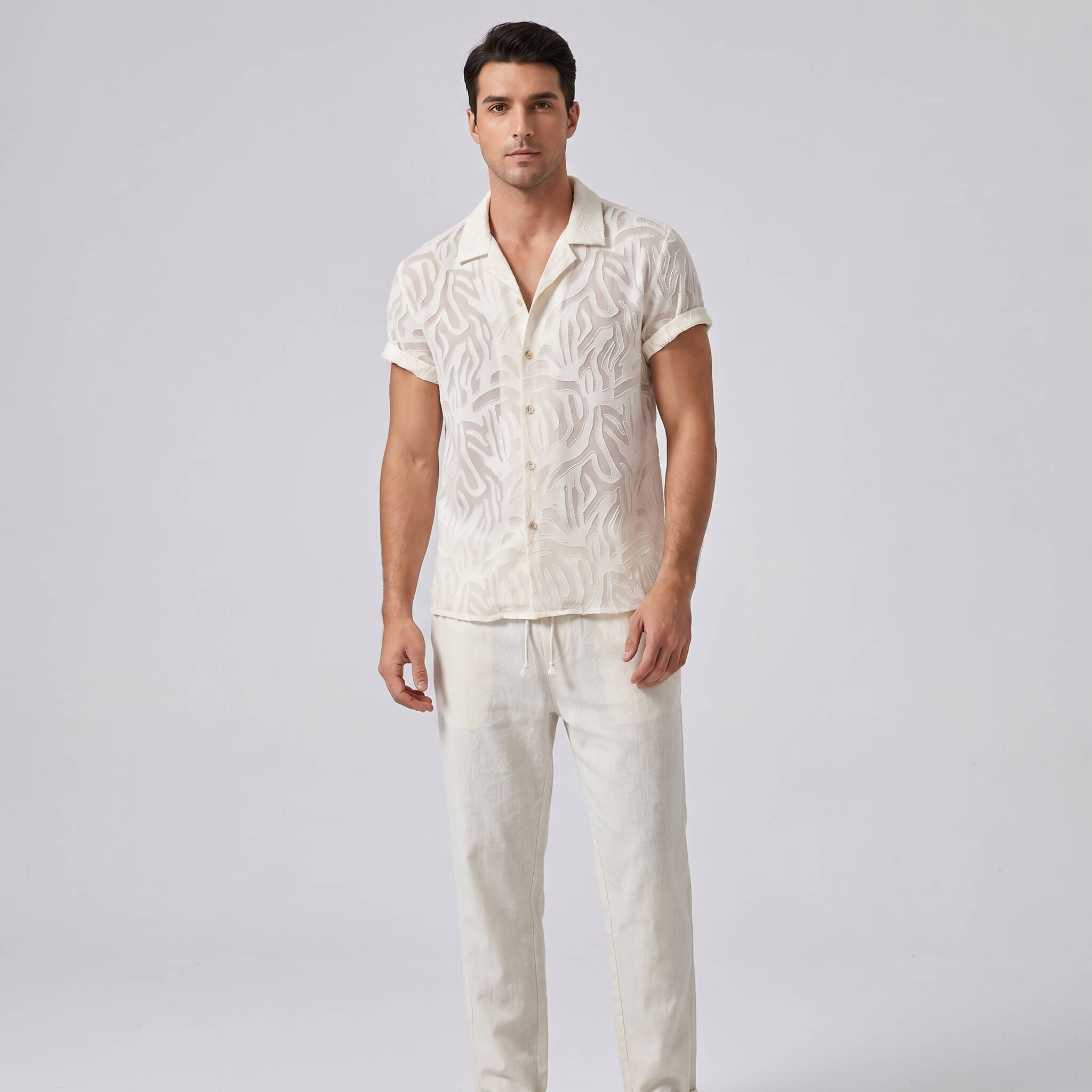 Man wearing a white patterned shirt and pants on a gray background