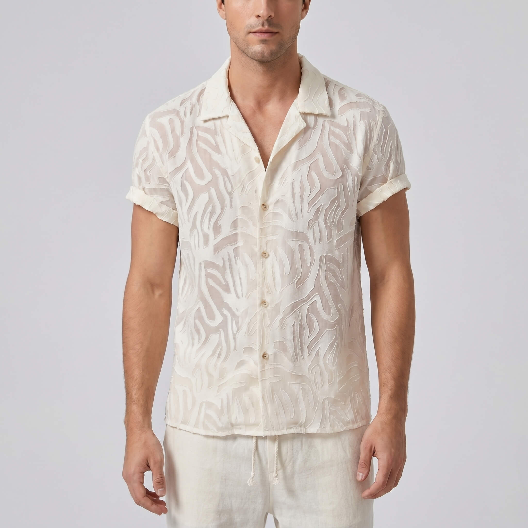 Man wearing a white patterned shirt and pants on a plain background