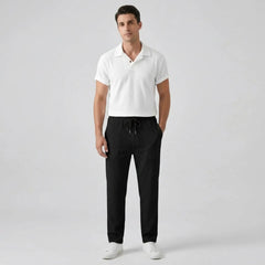 Man wearing a white polo shirt and black pants front view on a gray background