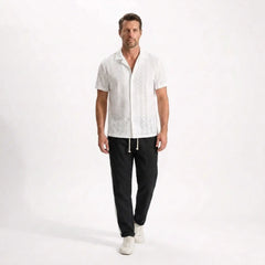 Man wearing a white shirt and black pants on a white background