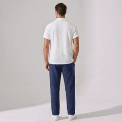 Man wearing a white shirt and blue pants against a plain background