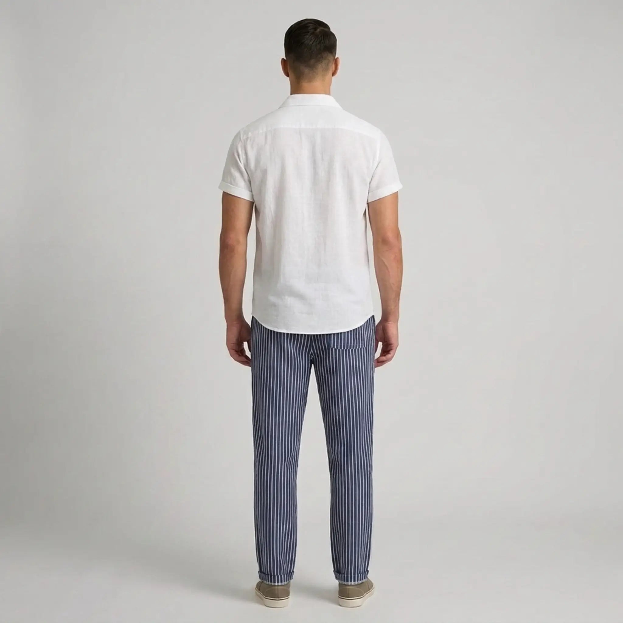 Man wearing a white shirt and blue striped pants on a gray background