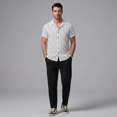 Man wearing a white striped shirt and black pants on a gray background