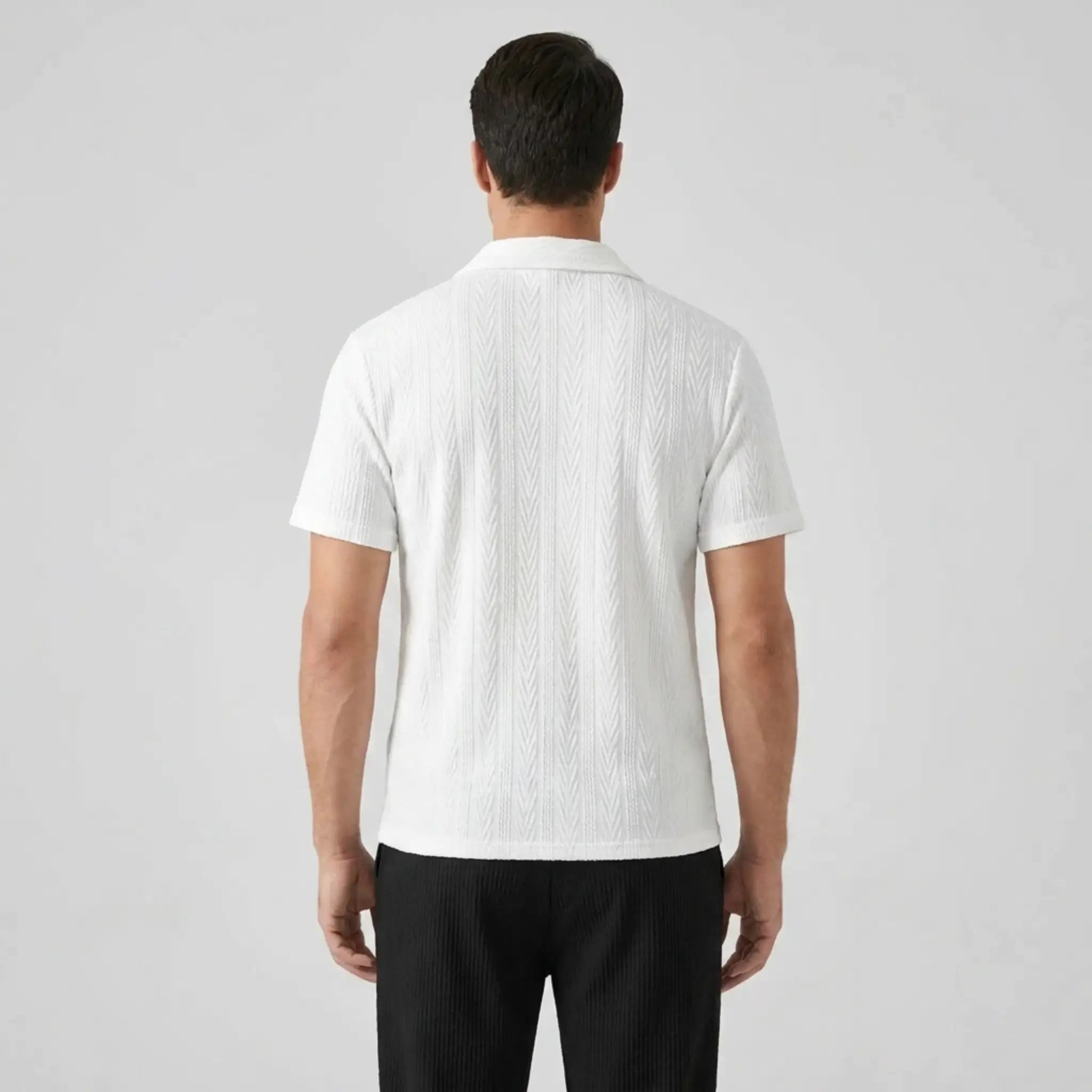 Man wearing a white textured polo shirt and black pants back view on a light gray background