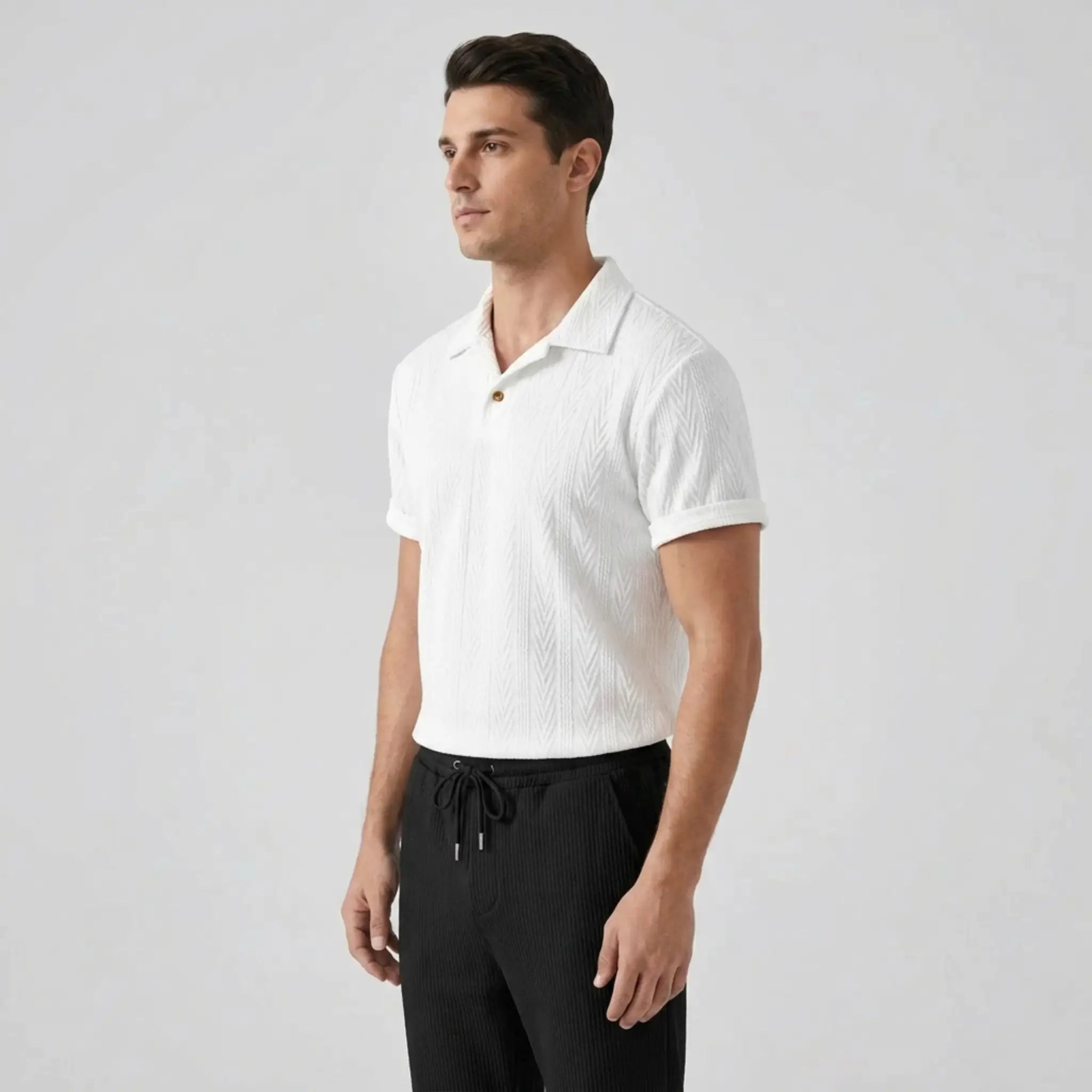 Man wearing a white textured polo shirt and black pants on a light gray background