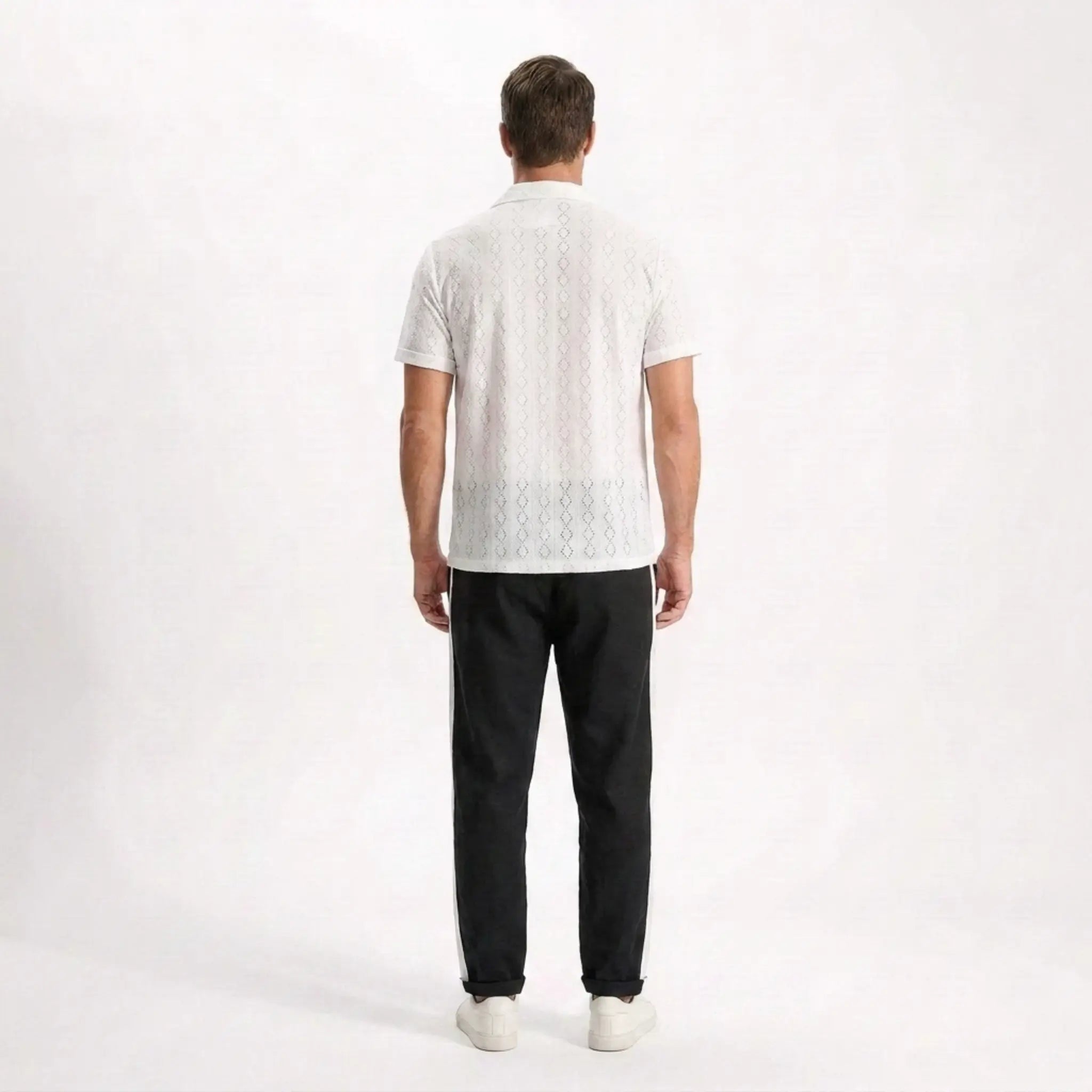 Man wearing a white textured shirt and black pants on a white background