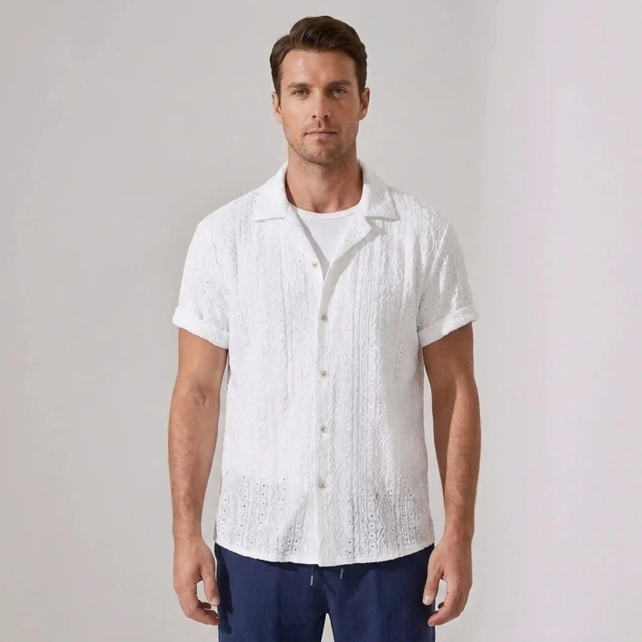 Man wearing a white textured short-sleeve shirt against a plain background