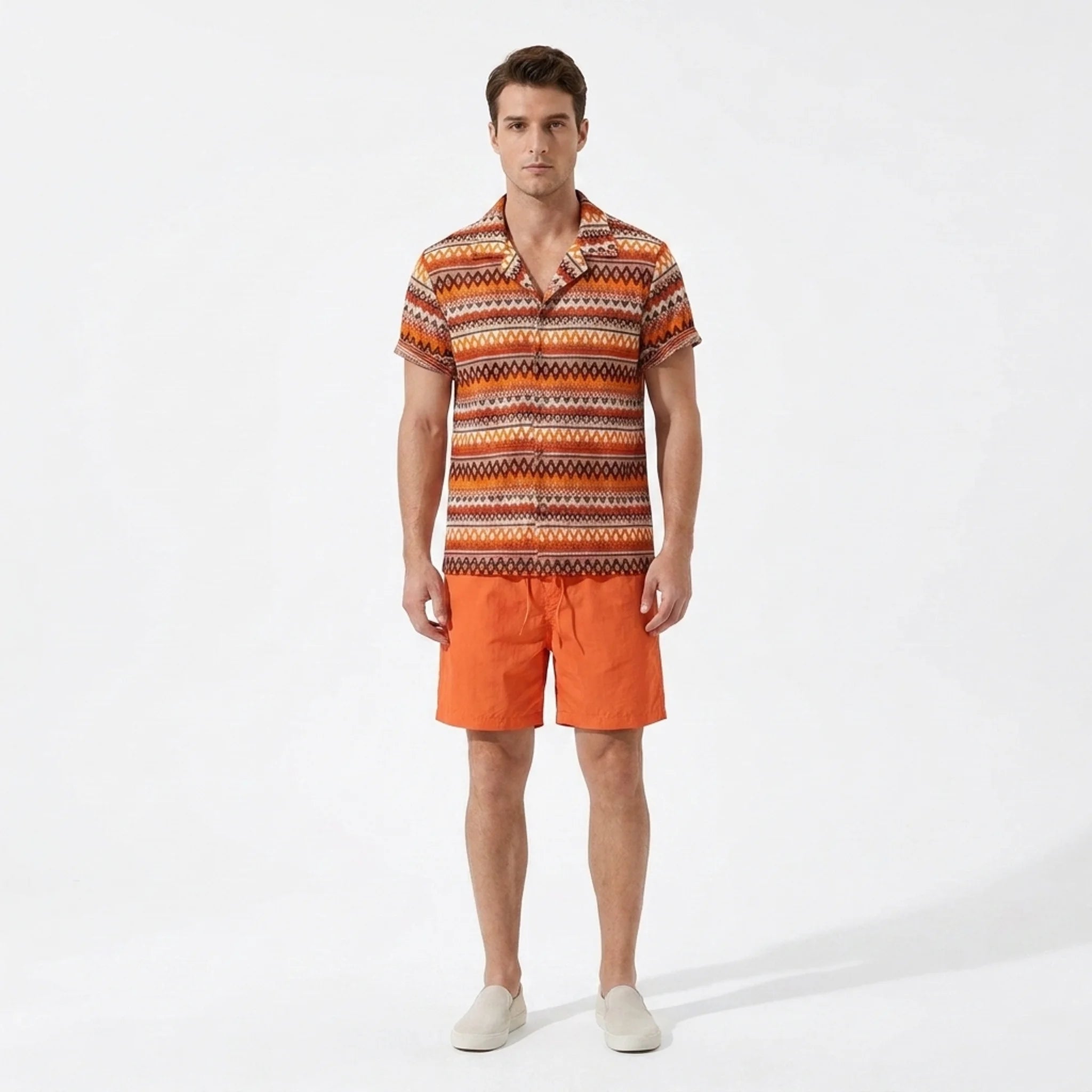 Man wearing an orange patterned shirt and shorts on a white background