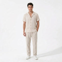 Front view of Man wearing beige geometric jacquard button up shirt and beige linen pants