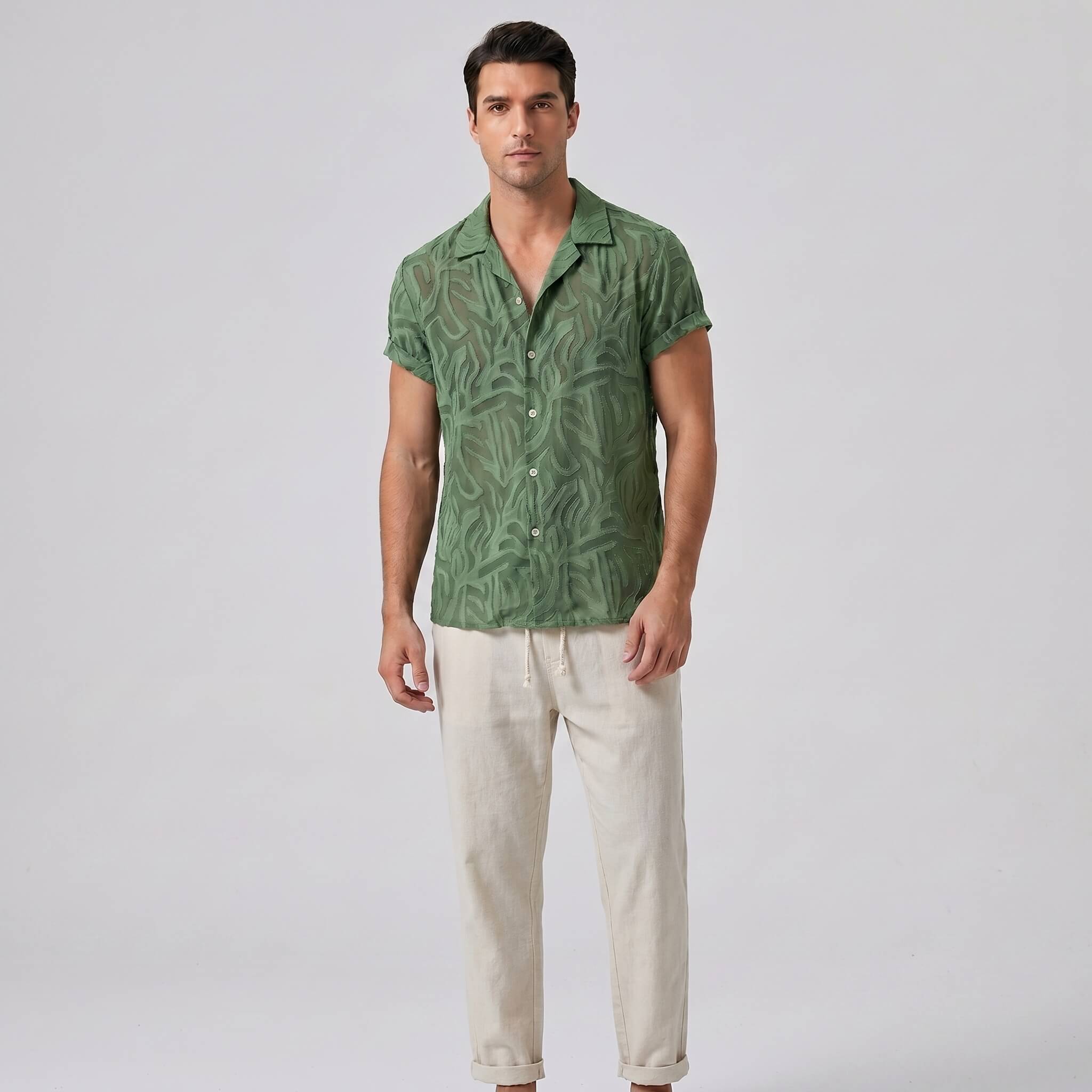 Man wearing green patterned short-sleeve Cuban shirt with white trousers