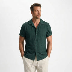 Man wearing a green shirt and beige pants on a white background