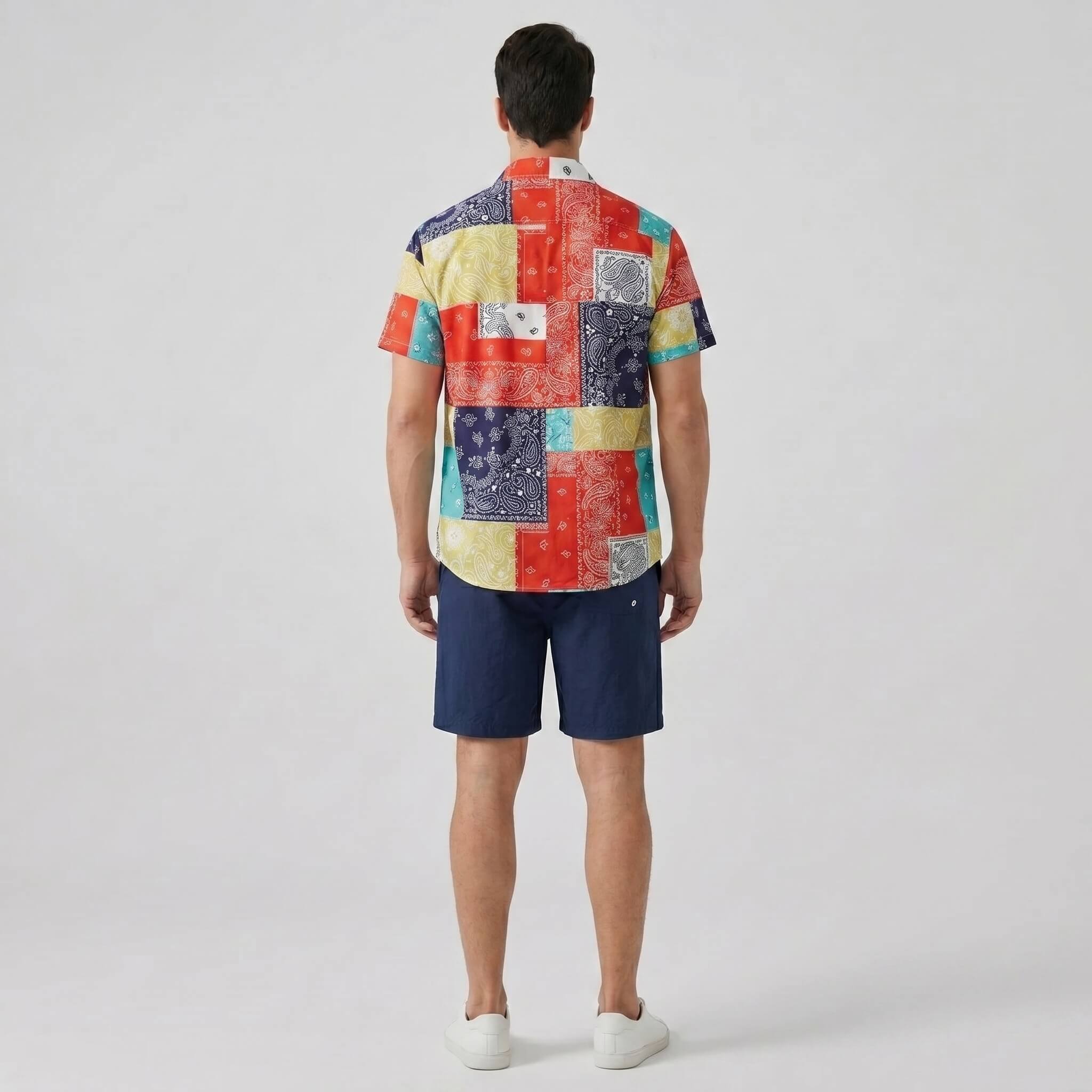 Person wearing a colorful patchwork shirt and navy shorts back view on a white background
