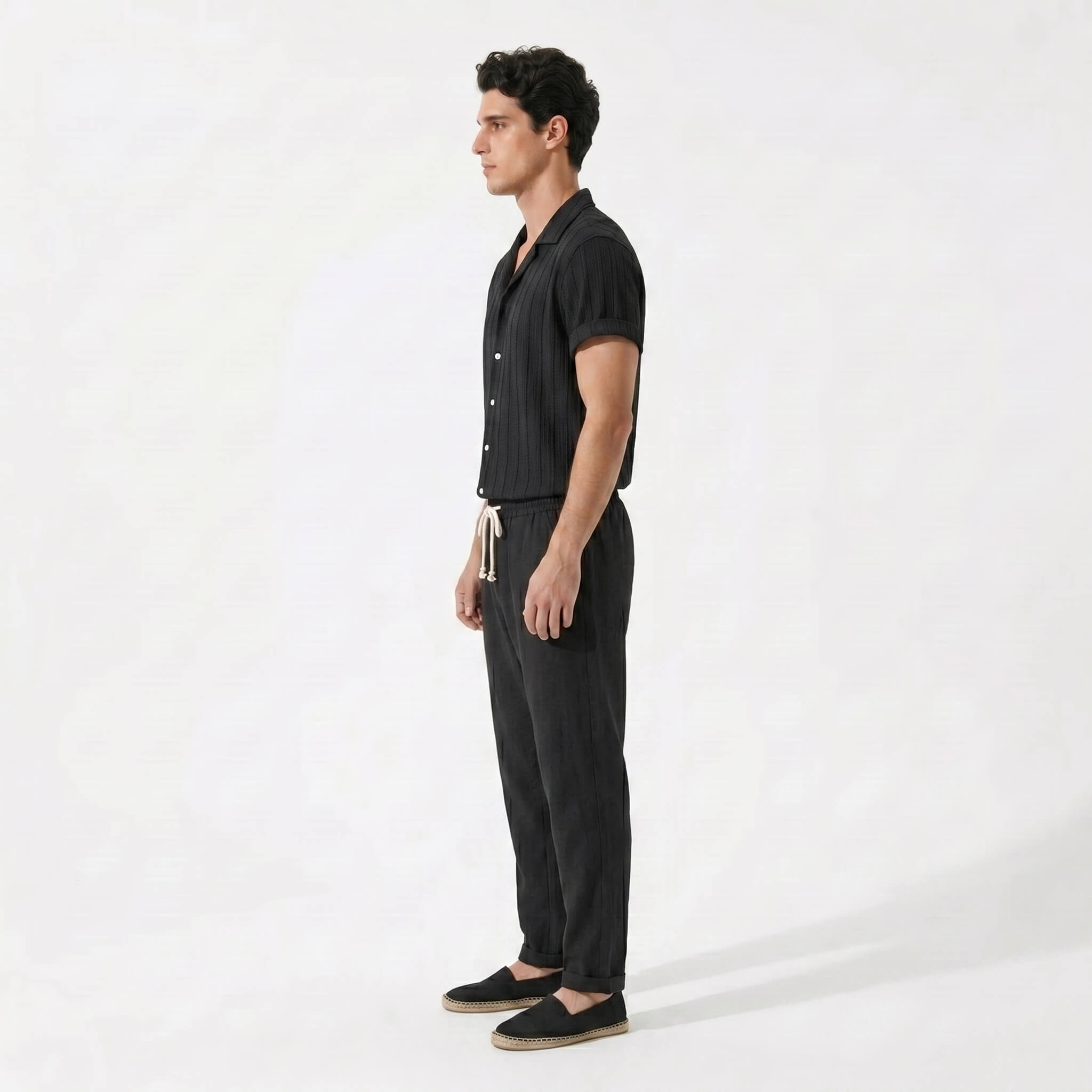 Side view of man wearing a black outfit with a white background