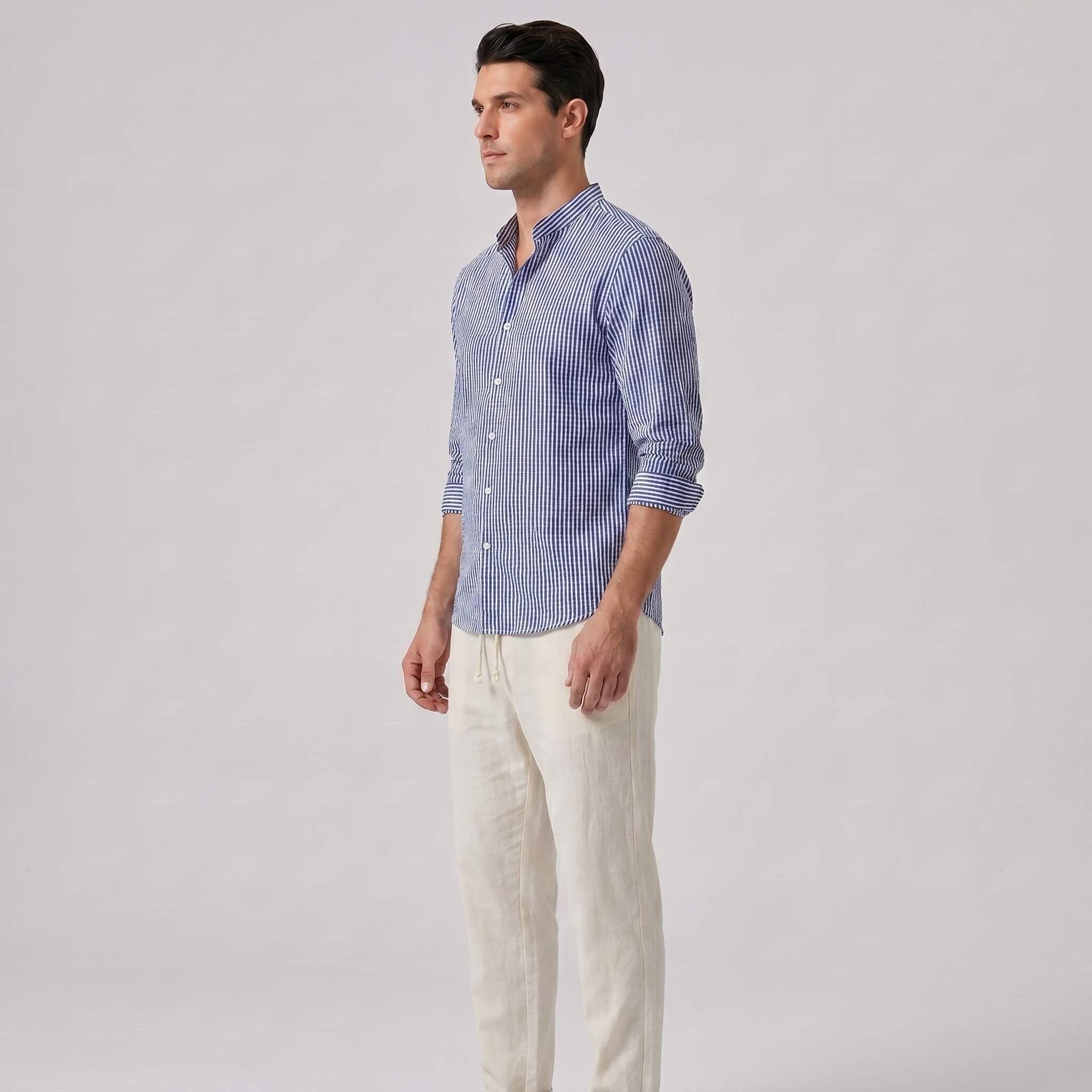 Side view of man wearing a blue striped shirt and white pants on a gray background