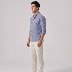 Side view of man wearing a blue striped shirt and white pants on a gray background