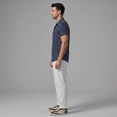 Side view of man wearing a navy striped shirt and white pants on a gray background