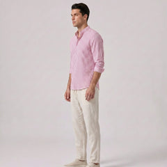 Side view of man wearing a pink checkered shirt and white pants on a light gray background