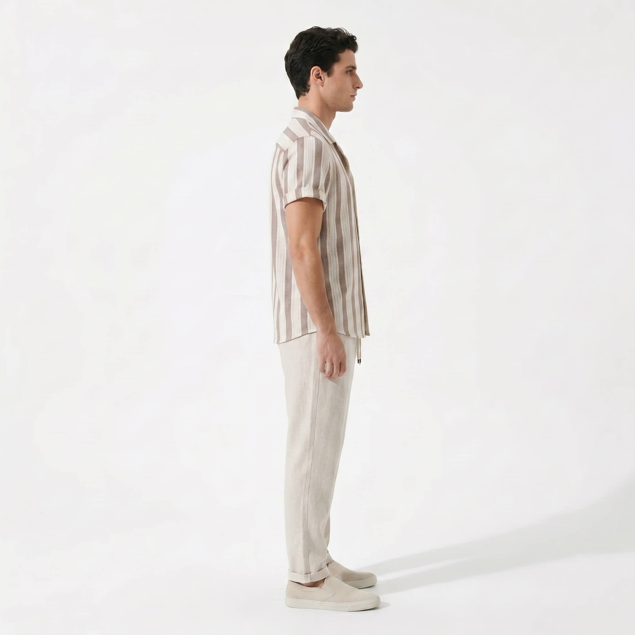 Side view of man wearing a striped shirt and beige pants on a white background