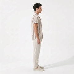 Side view of man wearing a striped shirt and beige pants on a white background