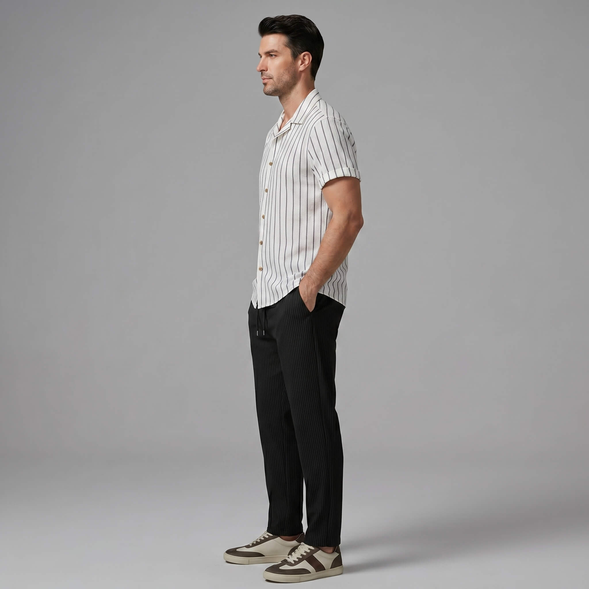 Side view of man wearing a white striped shirt and black pants on a gray background