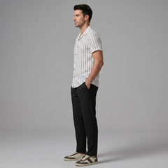 Side view of man wearing a white striped shirt and black pants on a gray background