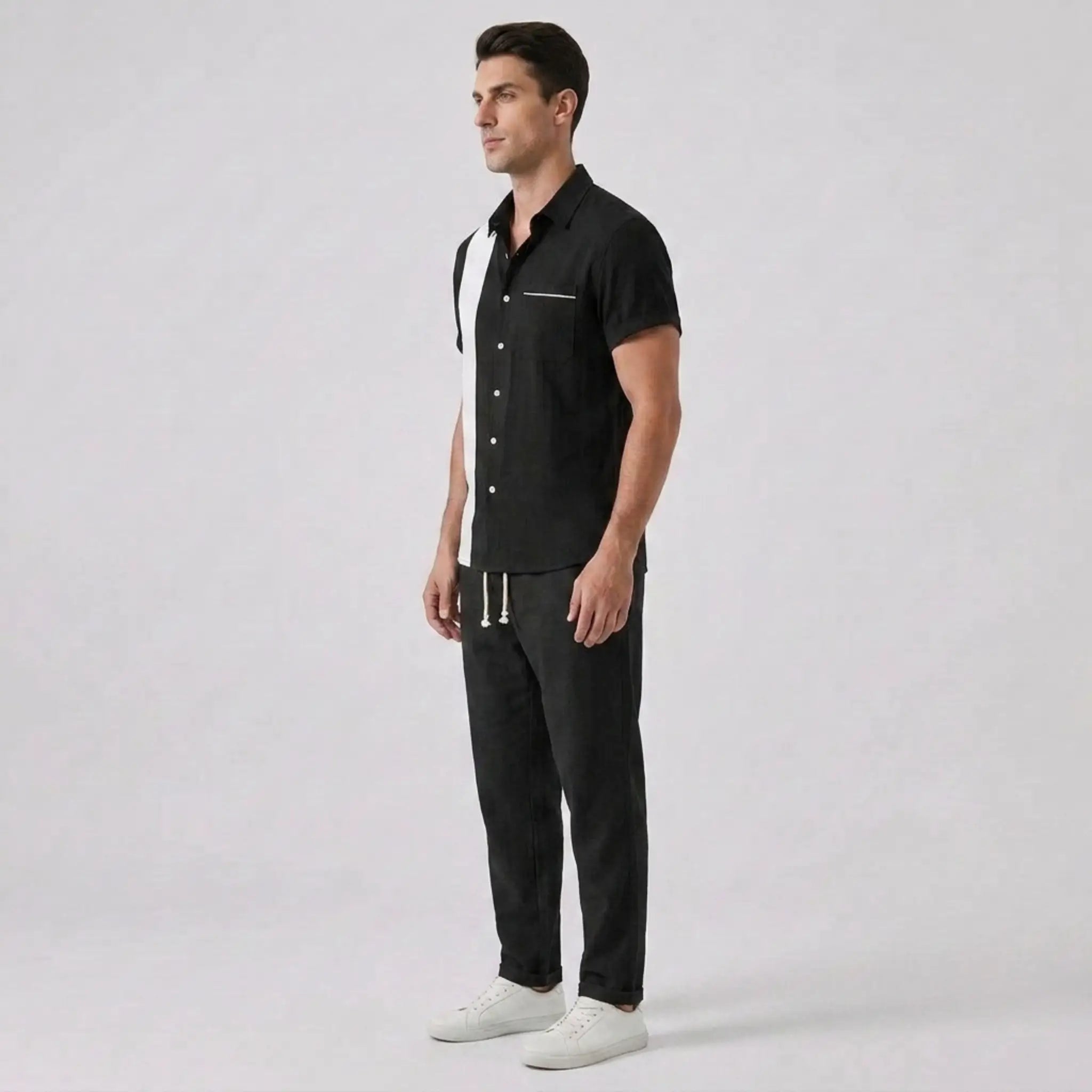 Side view of man wearing a black outfit against a gray background