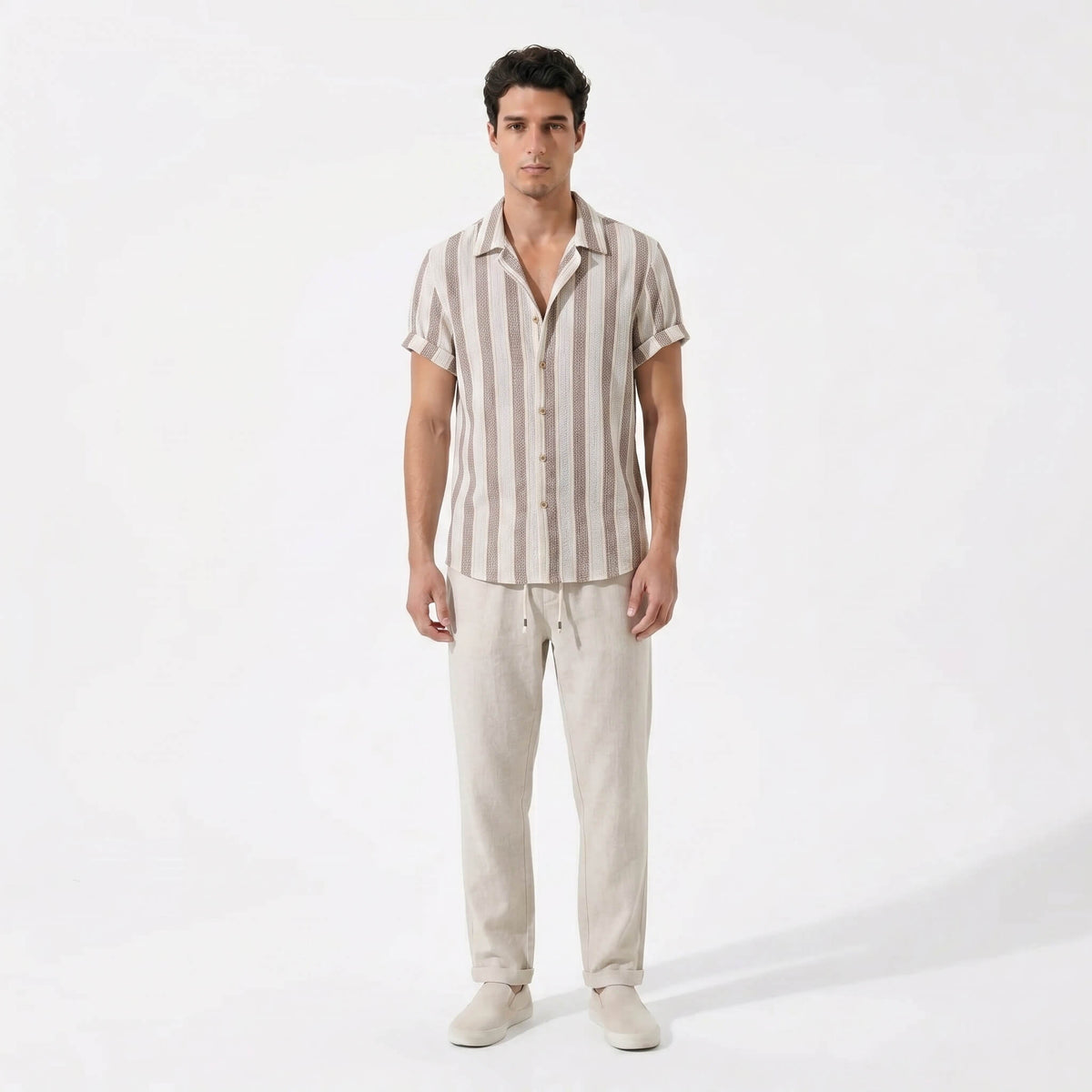 Man wearing a striped shirt and beige pants on a white background