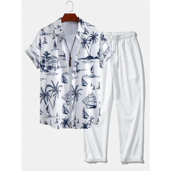 White shirt with blue island and palm tree pattern and white pants on a hanger against a white background