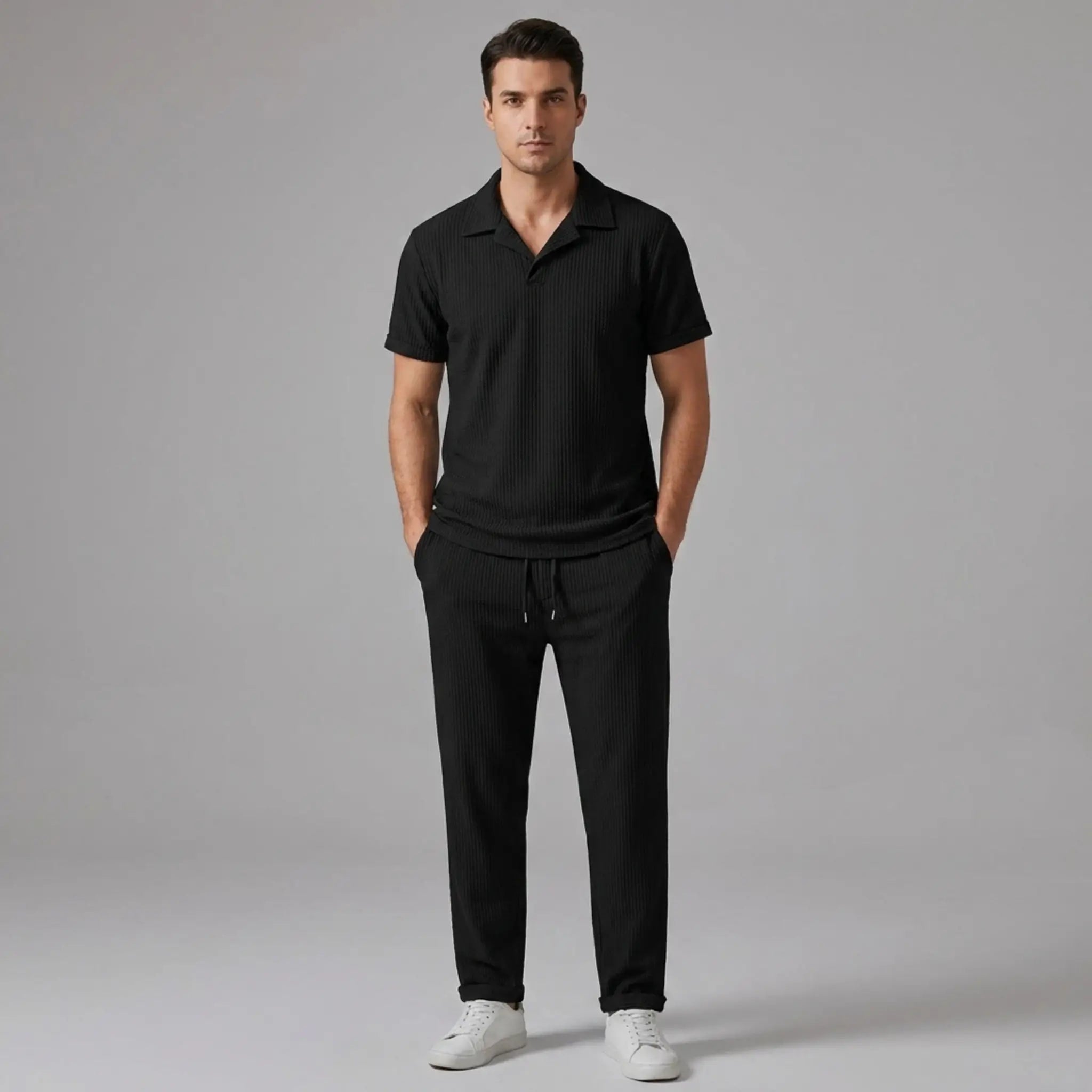 front view of man wearing a black polo shirt and trouser on a gray background