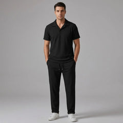front view of man wearing a black polo shirt and trouser on a gray background