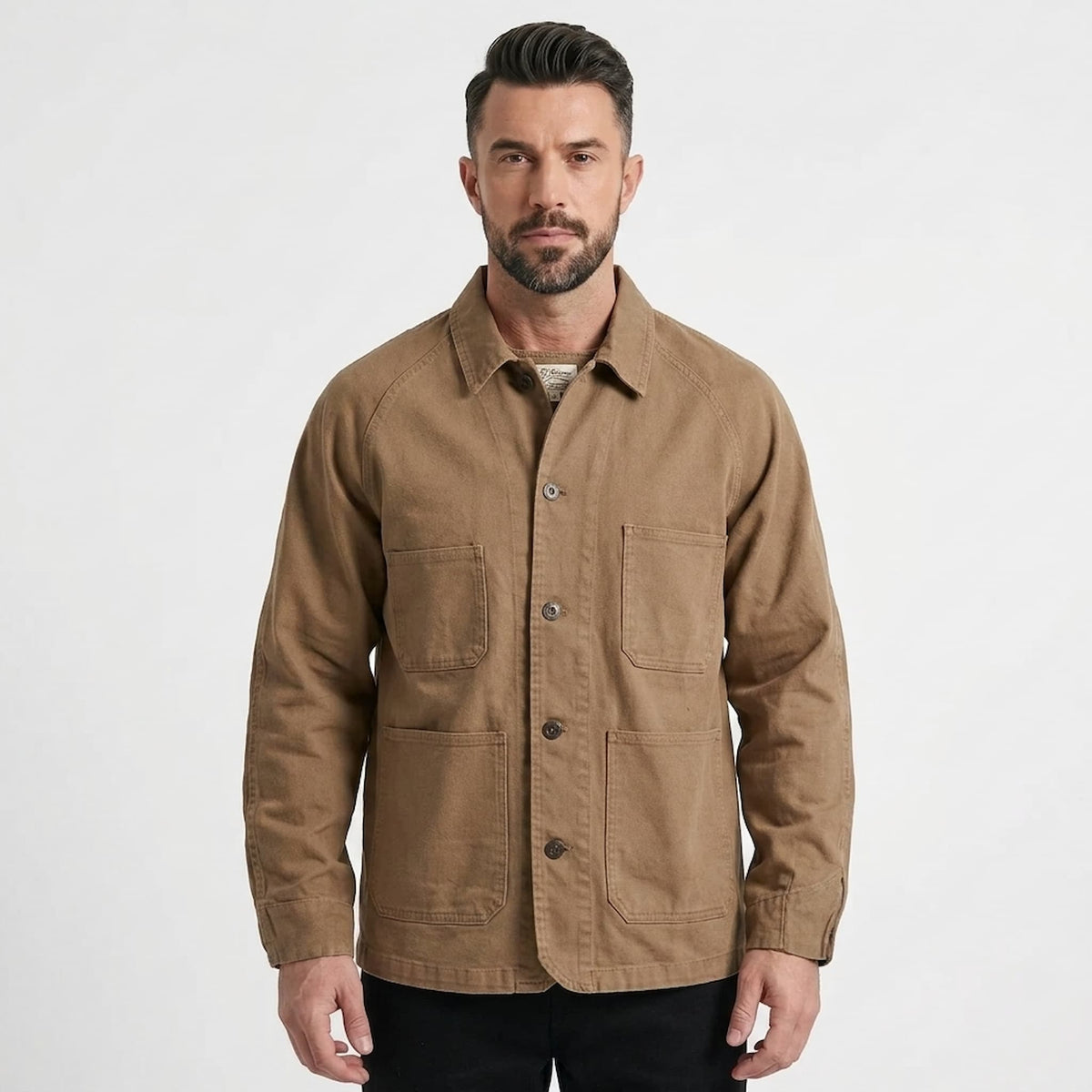 A man wearing a brown utility field jacket with four front pockets, shown against a plain light gray studio background.