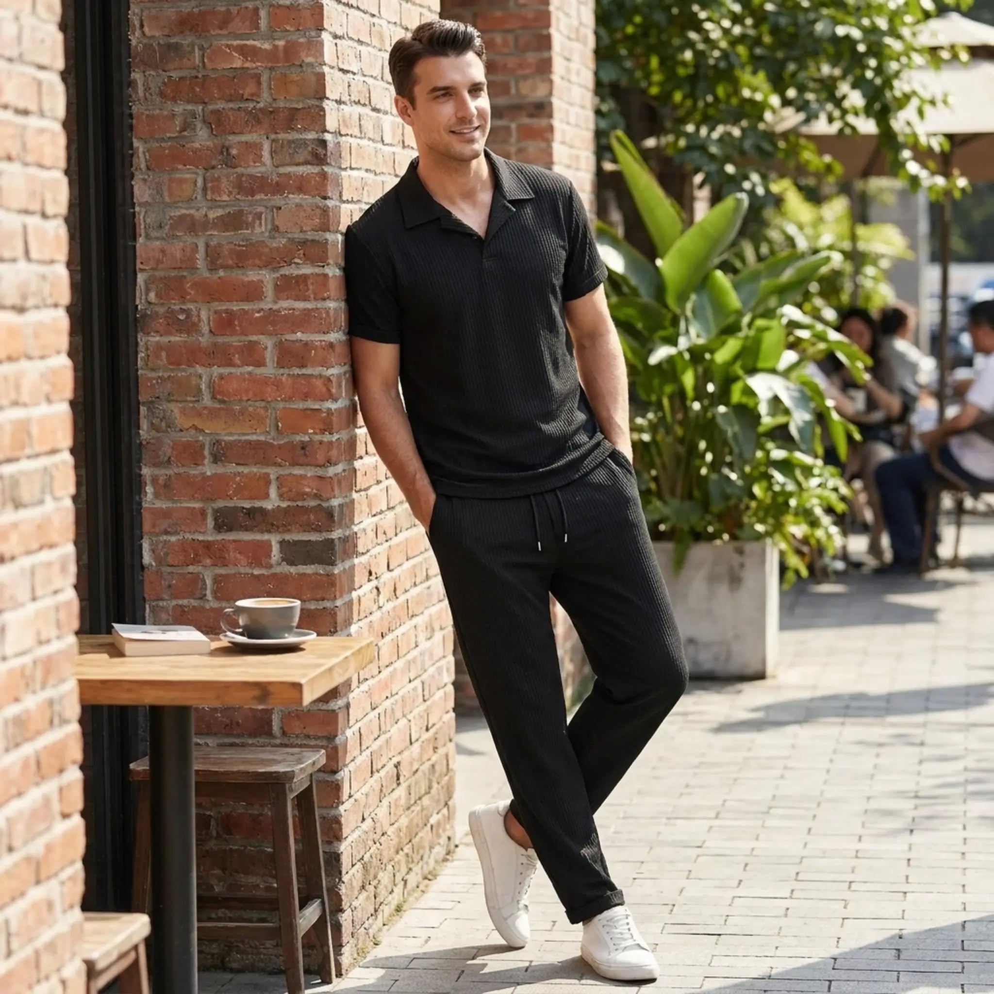 man leaning on a wall wearing black polo shirt and pant